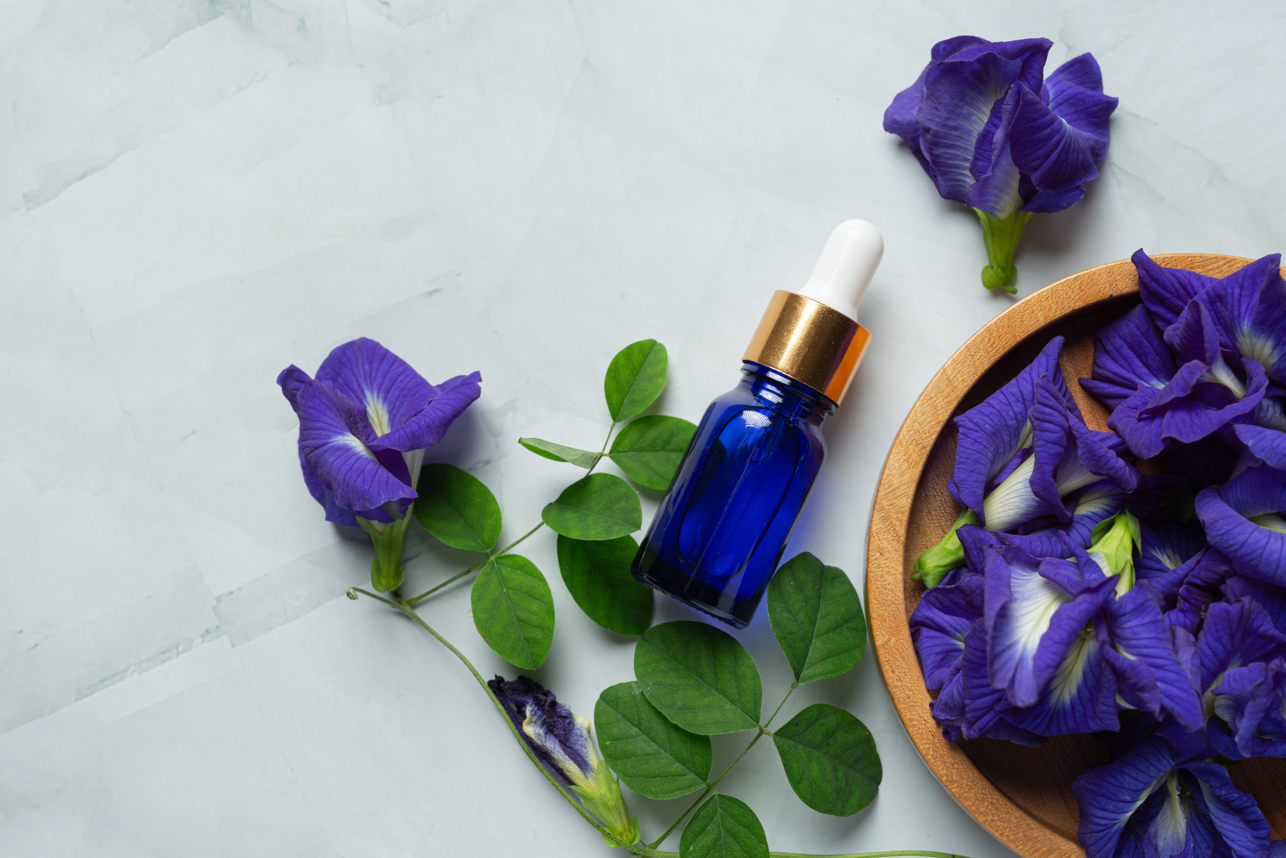 serum bottle of Butterfly Pea Flower oil put on white marble bac